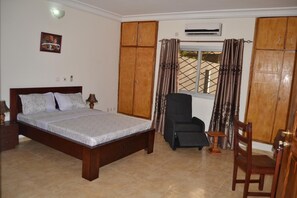 Une chambre à coucher comprenant un lit, une chaise, une armoire et un appareil de climatisation.