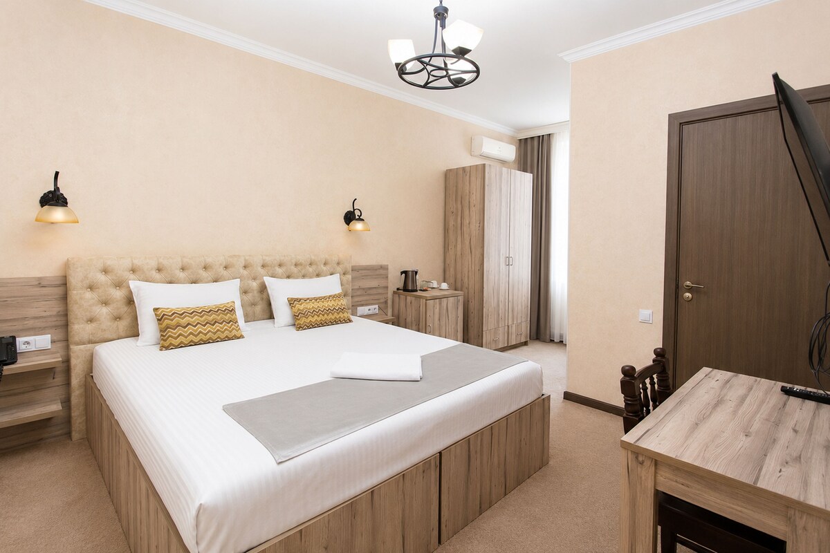 A bedroom with a large bed, bedside tables, a wardrobe, and a desk with a chair.