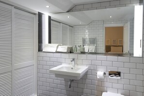 A modern bathroom with a white sink, mirror, and tiled walls.