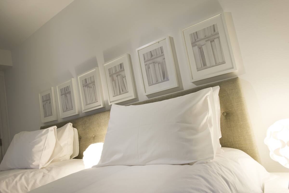 A hotel room with a neatly made bed, a headboard, and framed artwork on the wall.