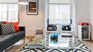 A modern living room with a sofa, coffee table, and a framed picture on the wall. - Urban Quarters Serviced Apartments (Dundee)