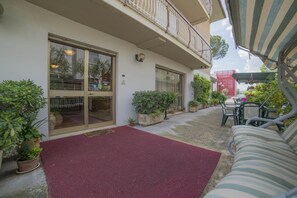 A covered outdoor seating area with a red carpet, potted plants, and a balcony with a railing. - Hotel Santa Maria (Assisi)