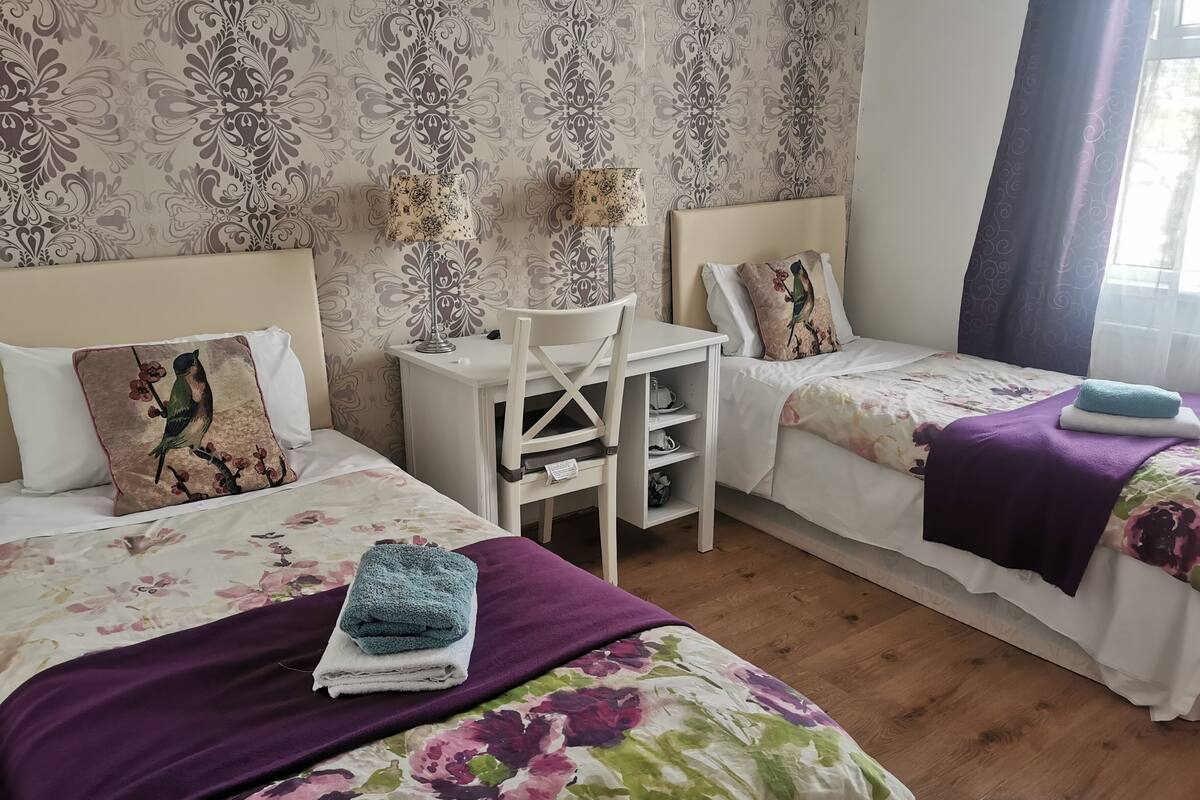 Une chambre d’hôtel avec deux lits, un bureau et une chaise.