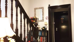 A staircase with a chandelier, a mirror, and a bookshelf with books. - Adams Guest House (Oxford)