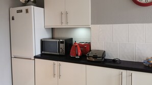 A kitchen with white cabinets, a microwave, a toaster, and a clock on the wall. - Adams Guest House (Oxford)