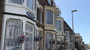 Una hilera de casas adosadas tradicionales con ventanales, una de las cuales muestra un cartel que dice 'Beckwood Hotel'.