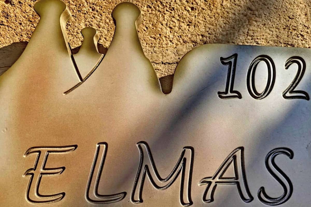 Una placa metàl·lica amb el número 102 i el nom 'ELMAS' gravat.
