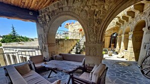 An outdoor seating area with stone flooring and a stone archway. - Cappadocia Antique House (Ürgüp)
