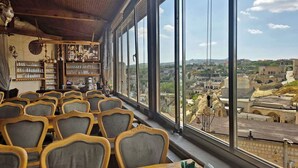 A restaurant with a view of a cityscape, featuring wooden furniture and shelves with glassware. - Cappadocia Antique House (Ürgüp)