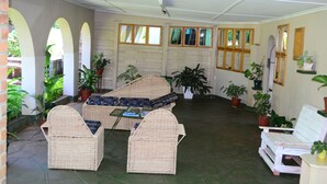 A covered patio area with wicker furniture, potted plants, and a view of the outdoors. - Breeze Guest House (Bulawayo)