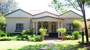 A two-story building with a symmetrical facade, large windows, and a central entrance with a covered porch. - Breeze Guest House (Bulawayo)