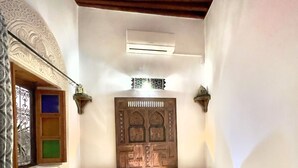 Una habitación estrecha con una mesa en el centro, dos sofás, una puerta decorativa y luces fijadas a la pared.