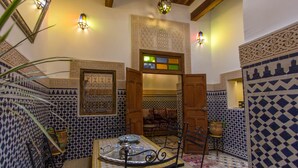 Un interior tradicional marroquí con suelo de azulejos, una puerta de madera y una mesa con una bandeja.