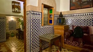 Una habitación con suelo de baldosas, una mesa de madera, un sofá y un cuadro en la pared.