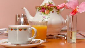 A table with a teapot, a cup of orange juice, a glass of water, and a flower. - The Warren Guest House (Carlisle)