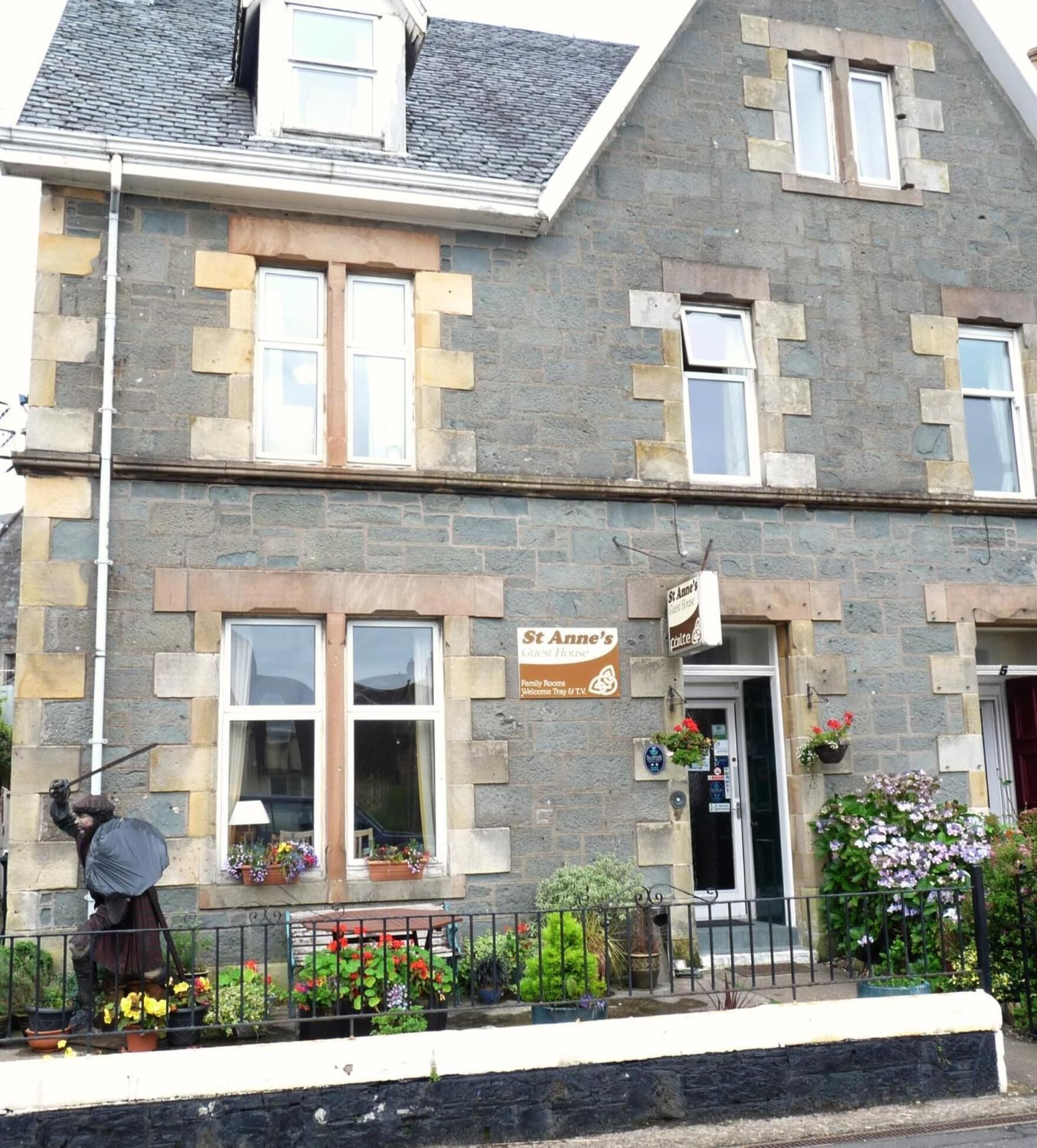 A stone building with a sign for "St Anne's Guest House" and "Family Rooms."