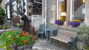 A stone building with a statue, outdoor seating, and flower boxes. - St. Annes Guest House (Oban)