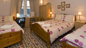 A hotel room with two beds, a desk, a chair, and a television. - St. Annes Guest House (Oban)