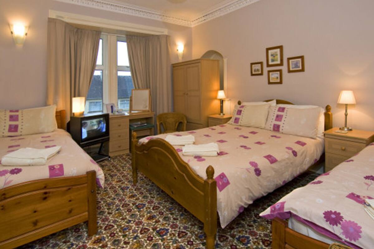 A hotel room with two beds, a desk, a chair, and a television.