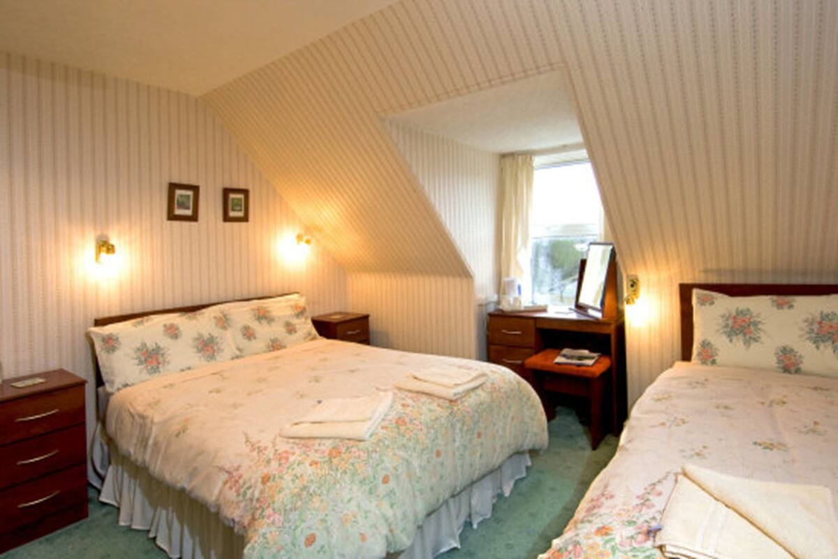 A bedroom with two beds, a desk, and a dresser.