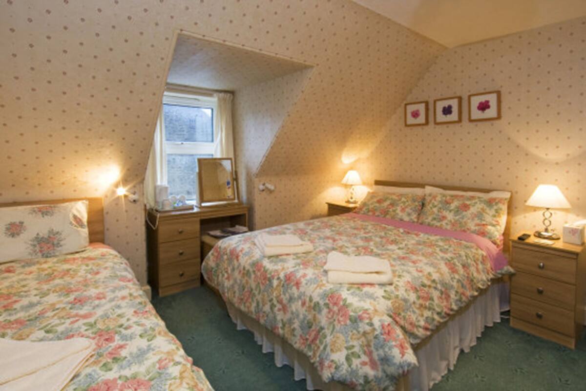 A bedroom with two beds, a window, and a dresser.