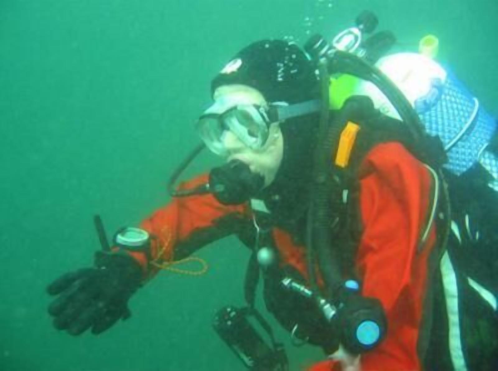 A diver in a red wetsuit with a scuba tank and regulator.