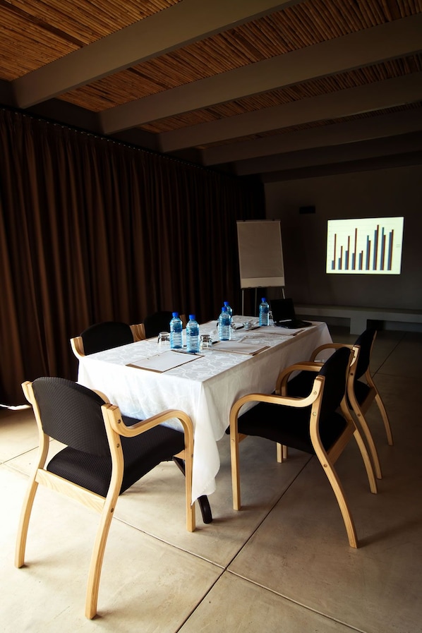Une salle de conférence avec une longue table, des chaises, des bouteilles d’eau et un écran de présentation.
