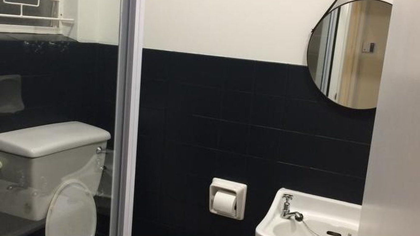 Een badkamer met toilet, wastafel en spiegel.