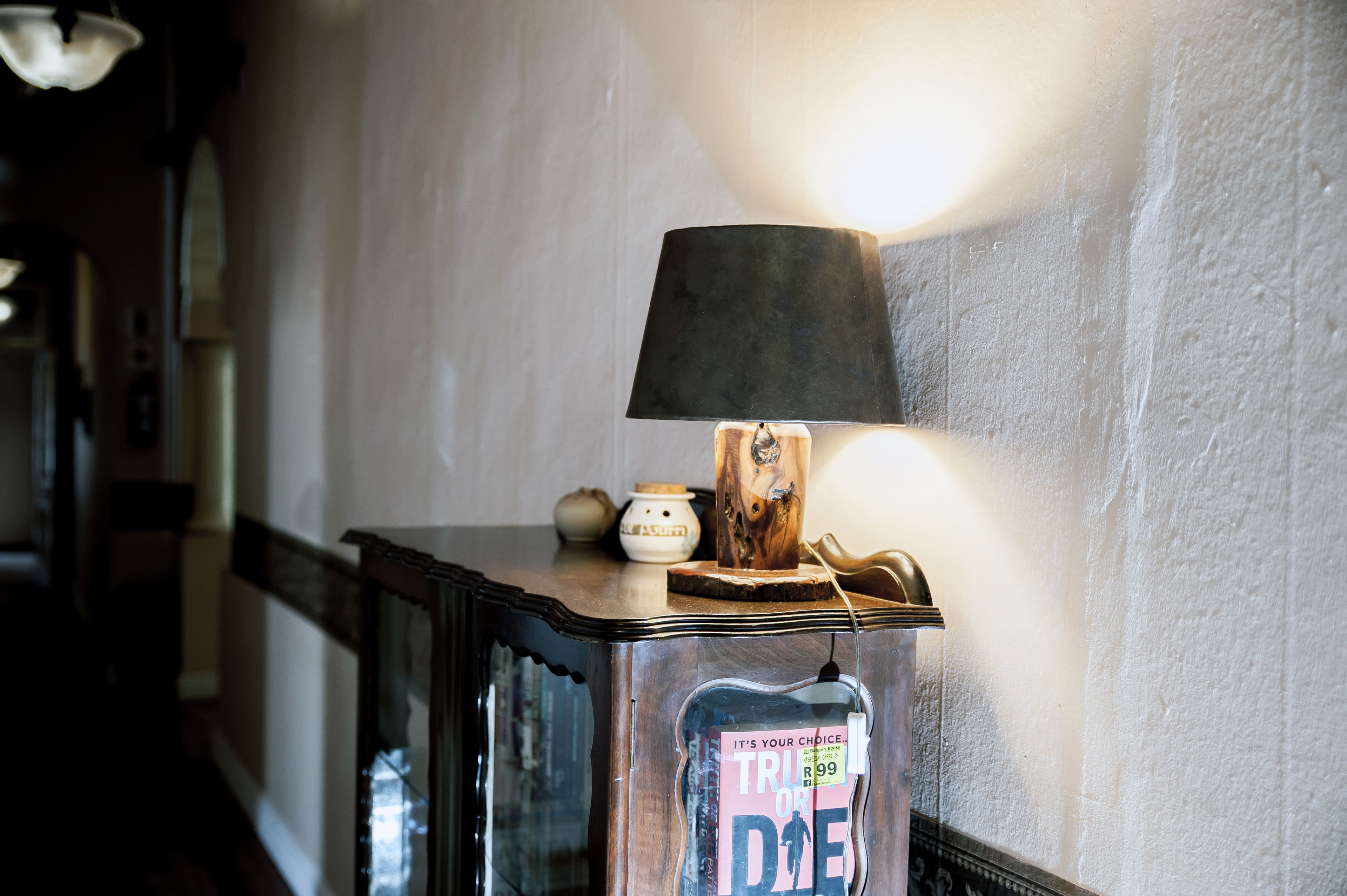 A lamp on a wooden table with a magazine on it.