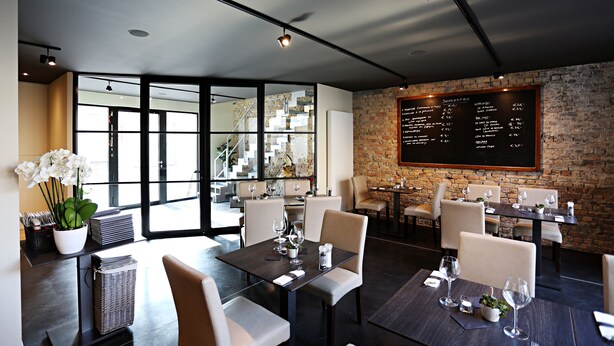 A modern restaurant with a brick wall, large windows, and a menu board.