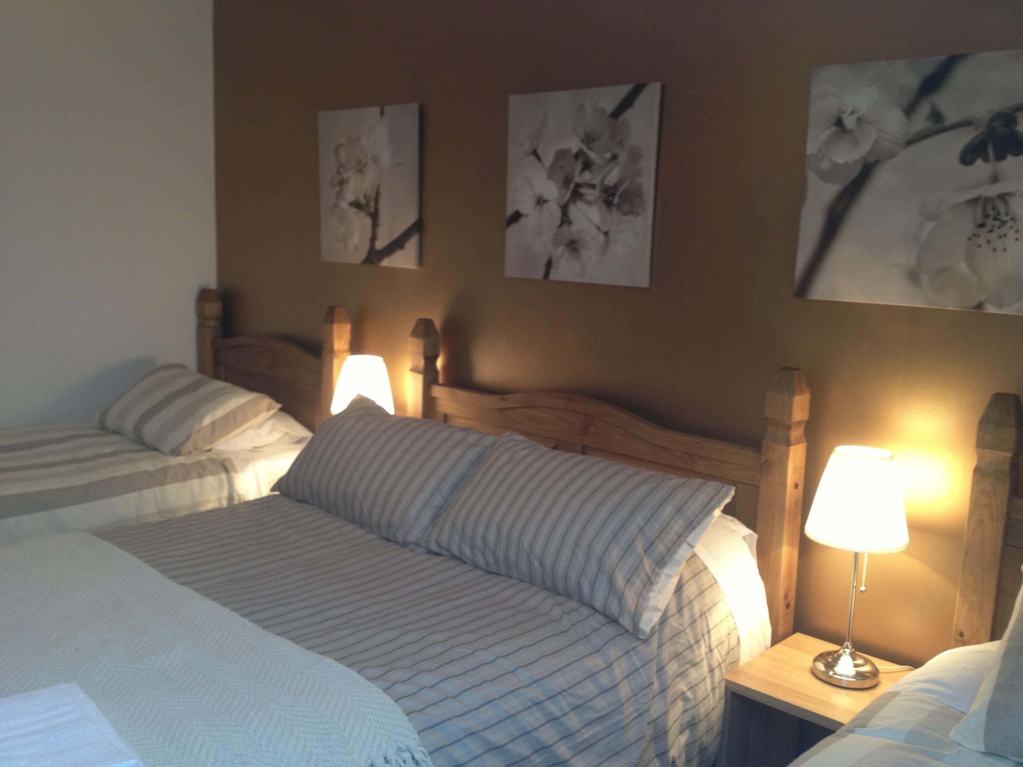Une chambre d’hôtel avec deux lits, une tête de lit en bois et des lampes fixées au mur.