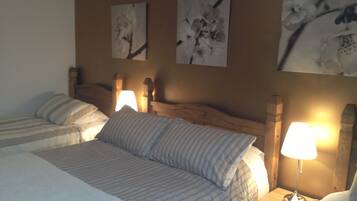 Une chambre d’hôtel avec deux lits, une tête de lit en bois et des lampes fixées au mur.