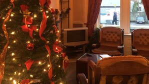 A living room with a decorated Christmas tree, a television, and two armchairs. - Glengorm Guest House (Oban)