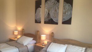 A hotel room with two beds, each with a wooden headboard, white bedding, and a nightstand with a lamp. - Glengorm Guest House (Oban)