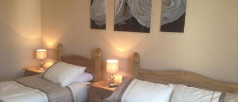A hotel room with two beds, each with a wooden headboard, white bedding, and a nightstand with a lamp.