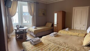 Un dormitorio con dos camas, un armario de madera, una mesita de noche, un televisor y una ventana con cortinas.