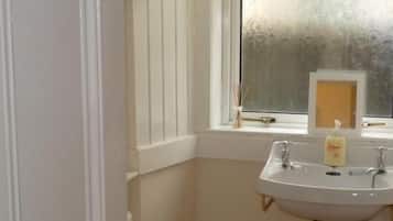 Un baño con un lavamanos blanco, un inodoro y una ventana.