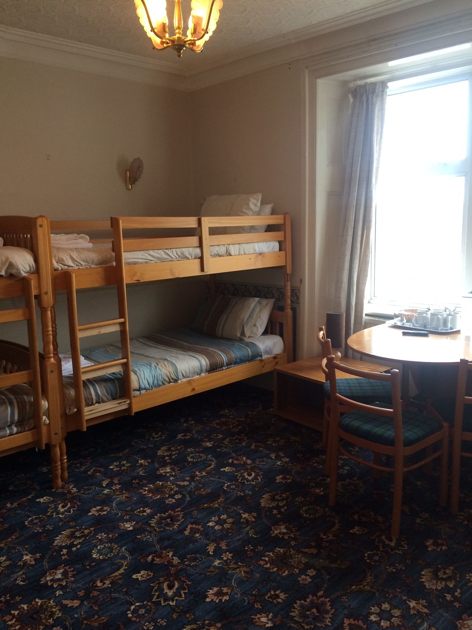 A room with bunk beds, a dining table, chairs, and a chandelier.