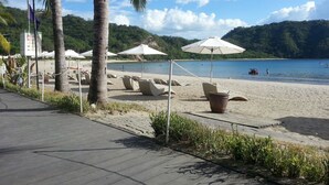 A beachside walkway with palm trees, beach chairs, and umbrellas. - Dr Calayan's 2BR Condo at Pico De Loro (Nasugbu)
