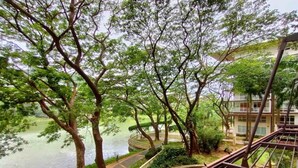 A riverside walkway with trees and a view of a building across the water. - Dr Calayan's 2BR Condo at Pico De Loro (Nasugbu)