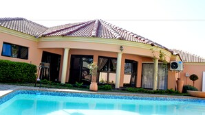 Ein Haus mit Pool, Ziegeldach und Garten.