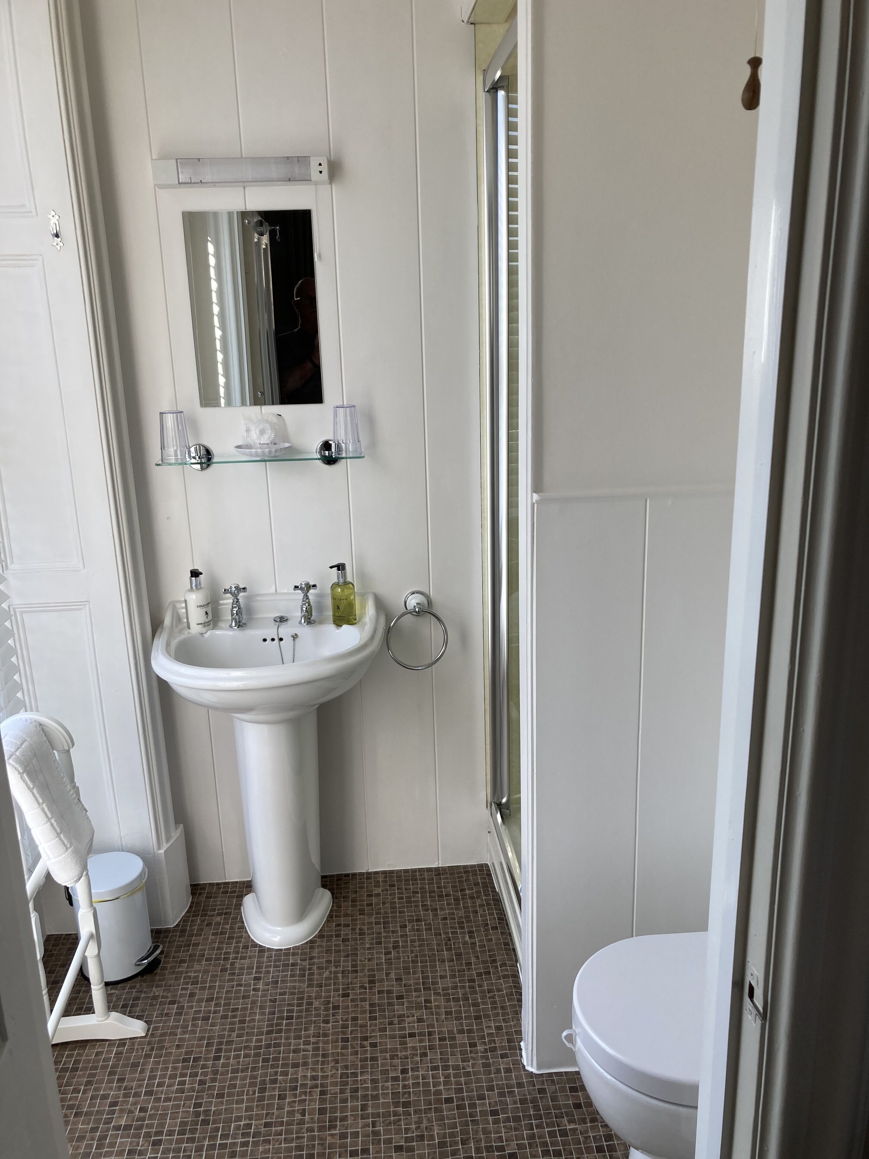 A bathroom with a white sink, mirror, and toilet.