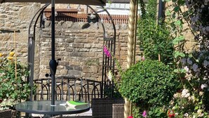 An outdoor patio with wicker furniture, a round table, and a hanging flower basket. - Thornsgill House B&B (Leyburn)