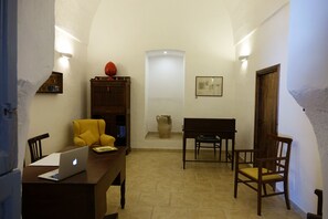 Una habitación con un escritorio de madera, una laptop, una silla amarilla y un armario de madera.