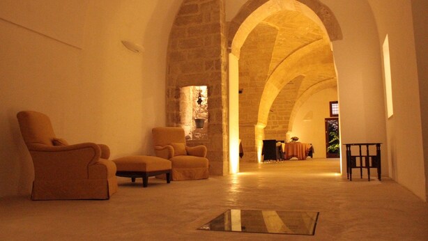 Un interior espaiós amb sostres de pedra arquejats, una zona de seients amb sofàs i una taula petita.