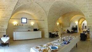 Àmplia zona de menjador amb una taula llarga preparada per l'esmorzar, que inclou diversos aliments i un ram de flors decoratiu.