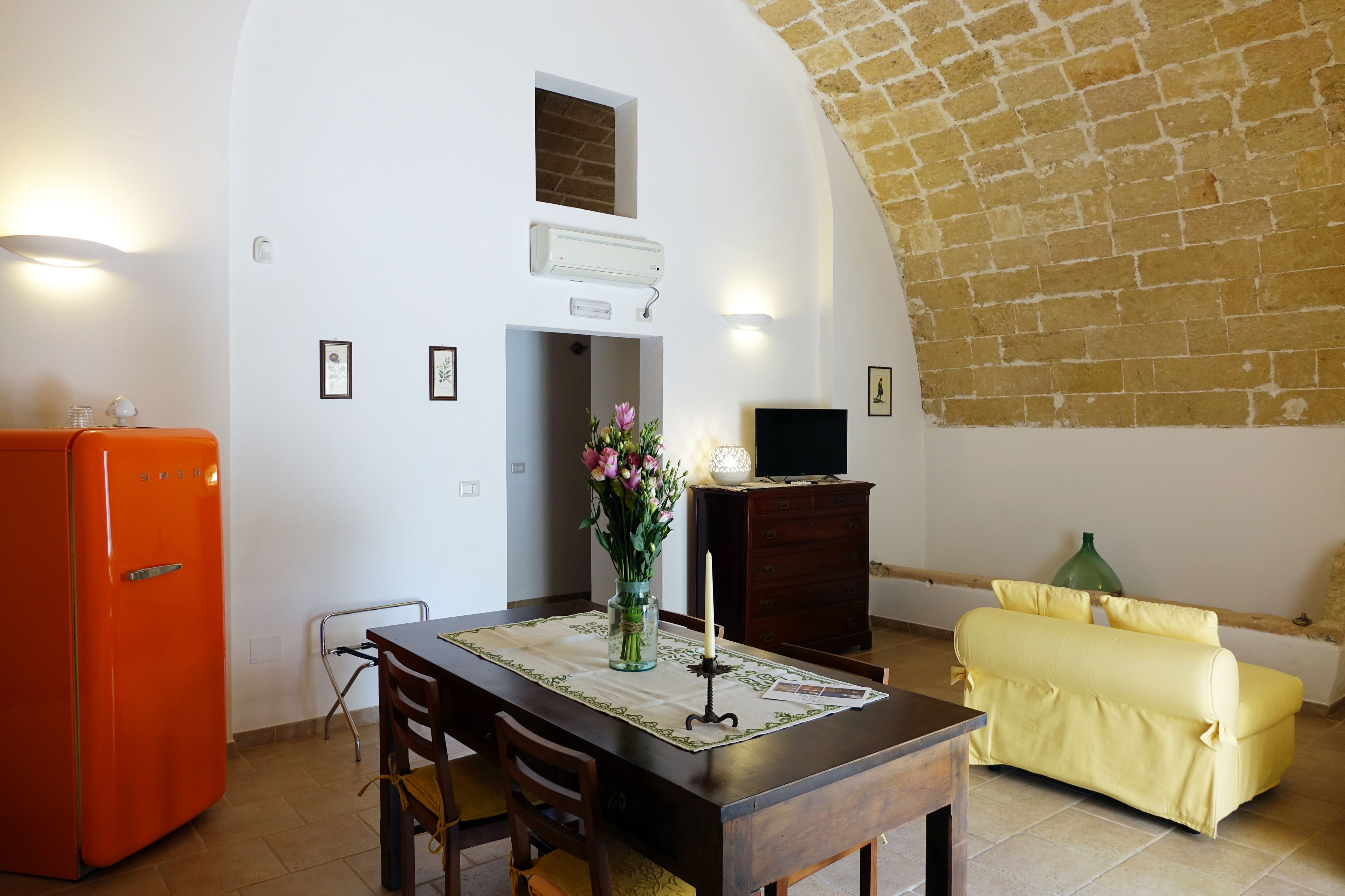 A compact living space with a dining area, a sofa, a TV, and a refrigerator.
