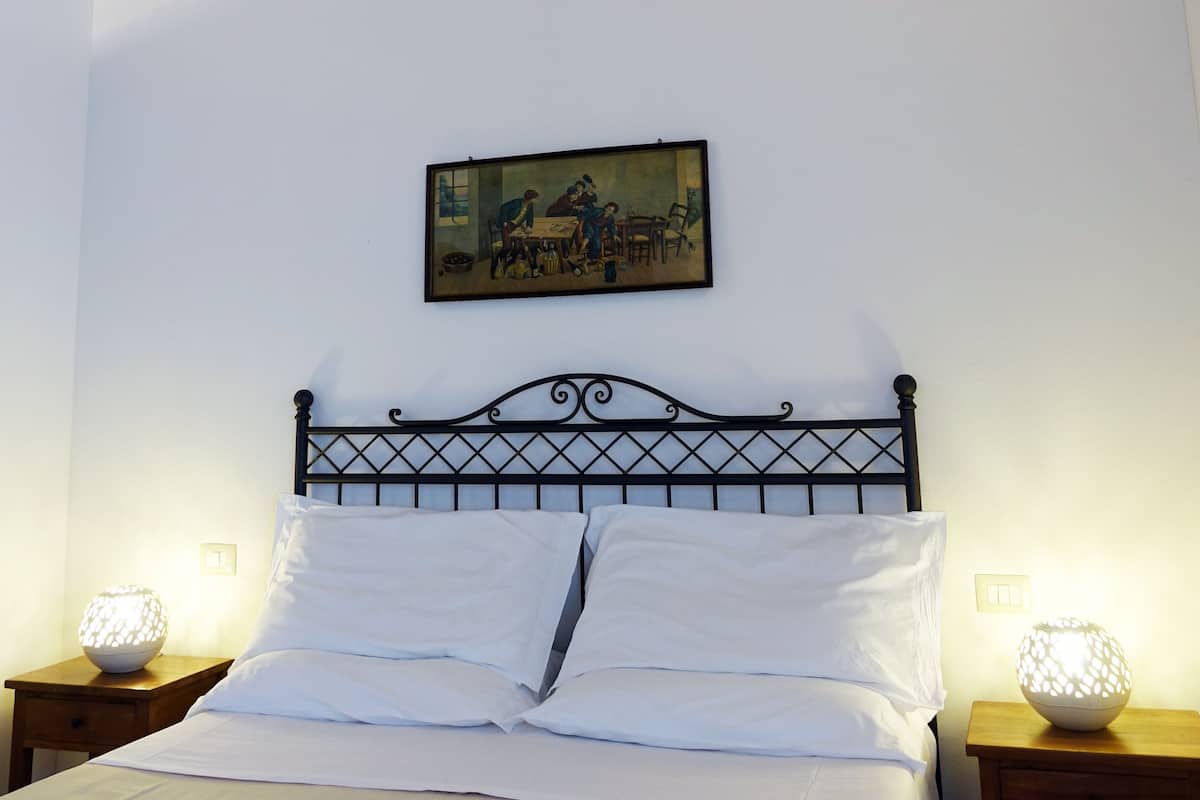 A bed with white linens, a metal headboard, and two bedside tables with lamps.