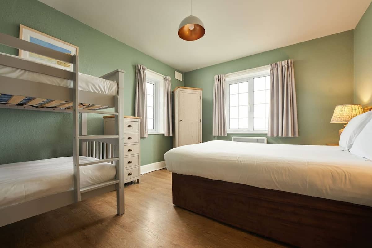 A room with bunk beds, a dresser, a wardrobe, and a large bed.
