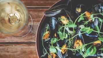 Un bol de moules et de légumes verts sur une table en bois.